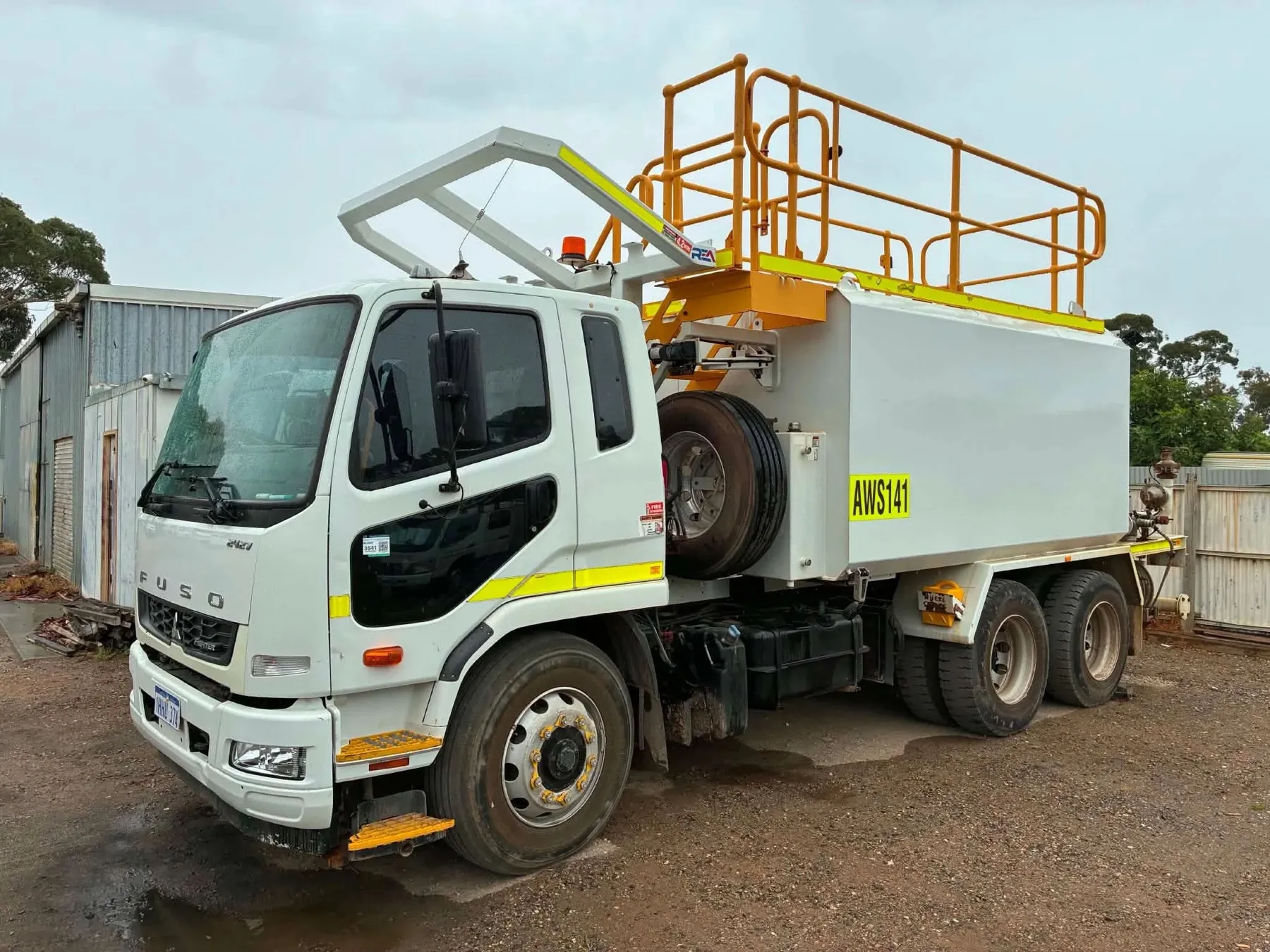 Their 14,000 litre water cart, a white Fuso tandem with yellow safety railings on top of the tank
